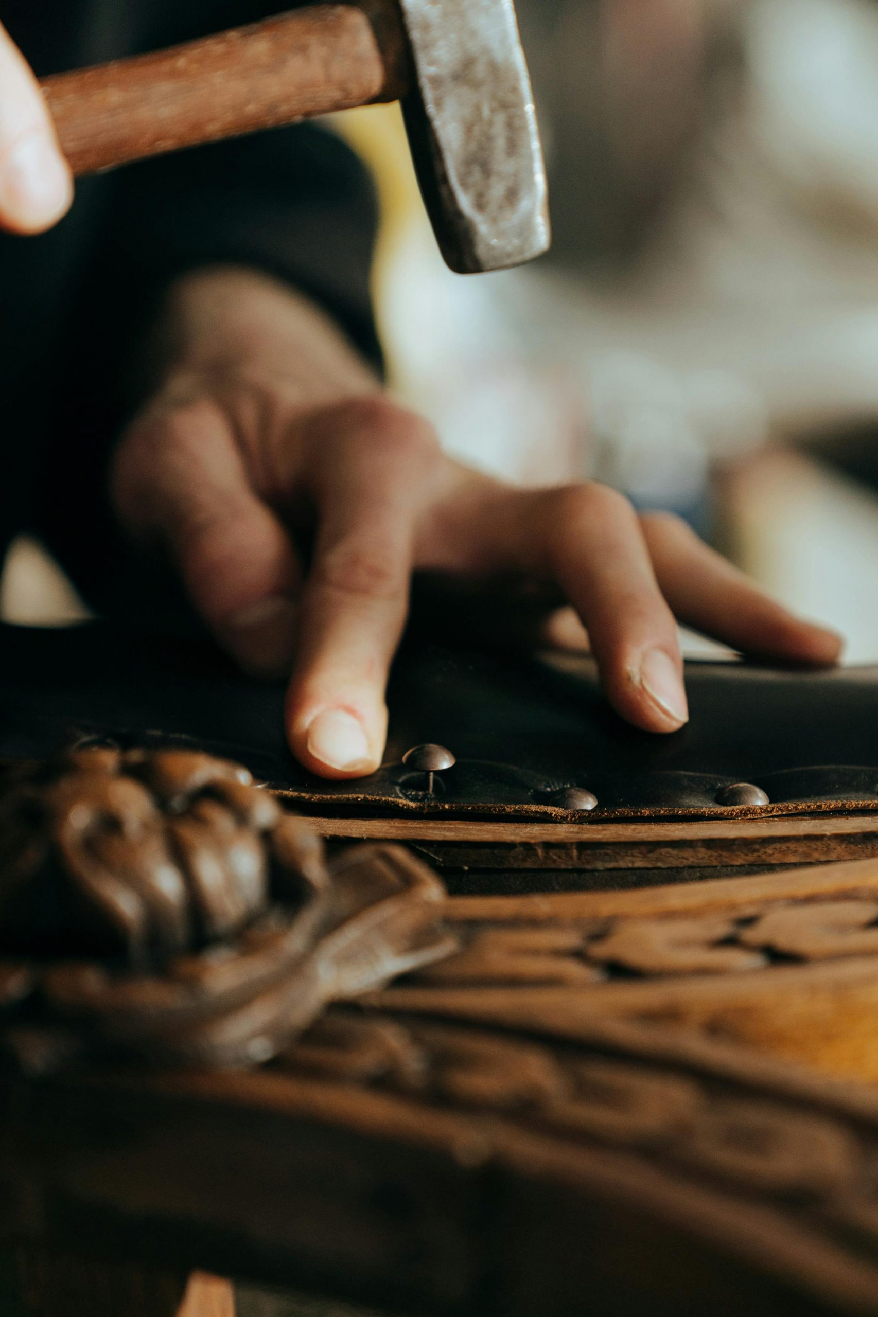 Close-up d'un artisan travaillant sur un meuble en bois vintage dans un atelier.