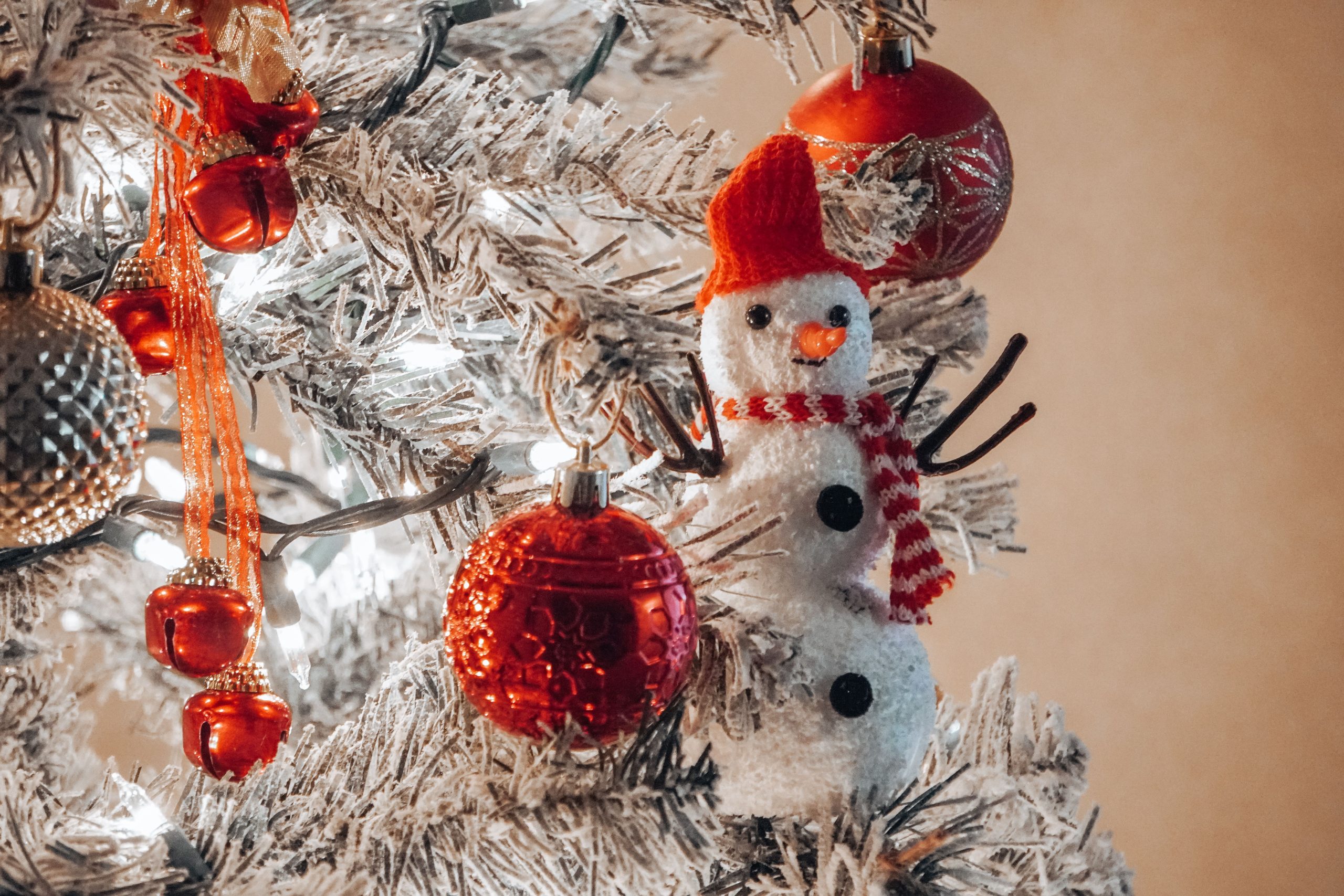 A close-up of a Christmas tree with red ornaments and a snowman decoration, evoking holiday cheer. Gros plan d'un sapin de Noël avec des ornements rouges et une décoration de bonhomme de neige, évoquant la joie des fêtes.