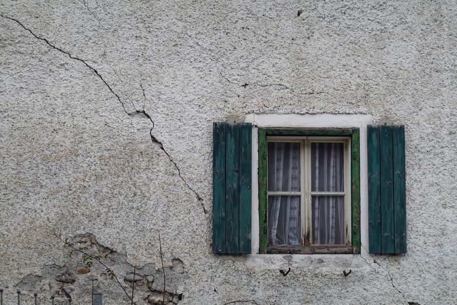 Fissures sur un vieux mur en béton près d’une fenêtre